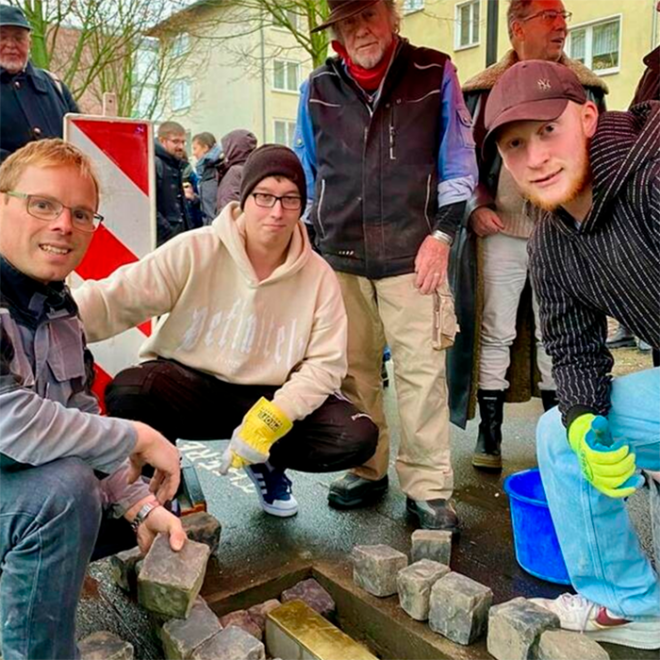 stolperschwelle_12_2023_01 Im Einsatz: Fachlehrer für Bautechnik, Steffen Wickert mit den Schülern Stefan Höhne und Julius Liebig (von links). Dahinter steht Gunter Demnig. Foto: christina hein